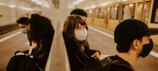 Mulher de máscara em estação de metrô.
