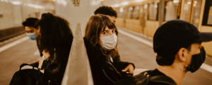 Mulher de máscara em estação de metrô.