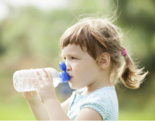 Menina bebendo água para evitar desidratação 