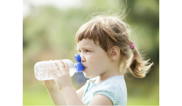 Menina bebendo água para evitar desidratação 