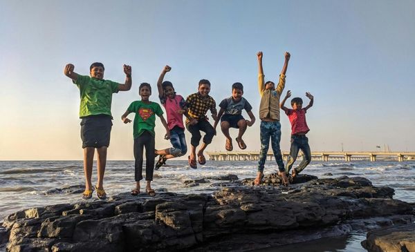 Crianças pulando de uma pedra em uma praia