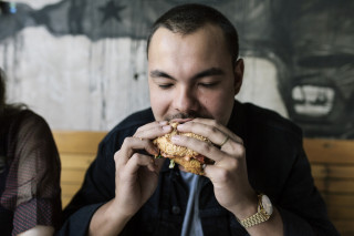 Homem comendo hamburguer