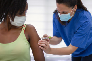 Mulher tomando vacina no braço esquerdo