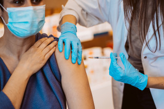 Enfermeira aplica vacina no braço de mulher