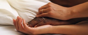Homem e mulher negros estão deitados com as mãos entrelaçadas