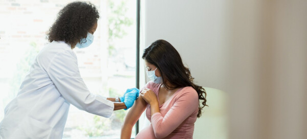 Enfermeira aplicando vacina em braço de gestante