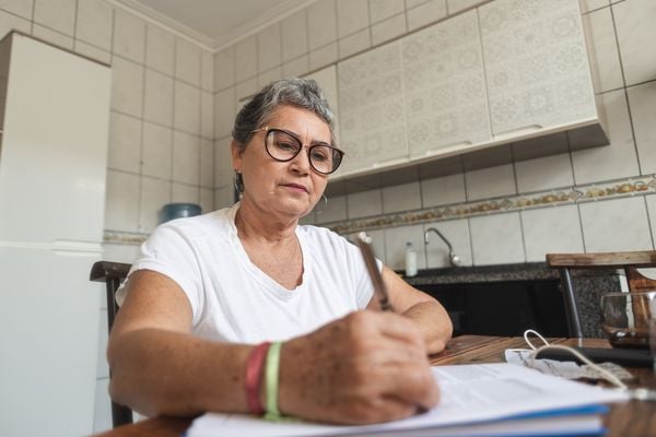 Mulher idosa escrevendo em folha de papel