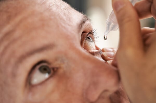 Homem pingando colírio no olho