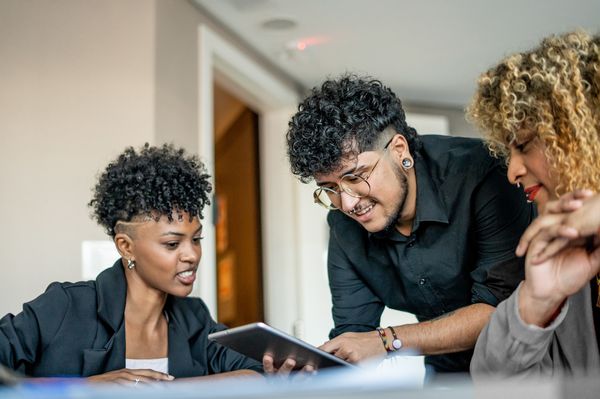 Três jovens trabalhando juntos, com feições alegres