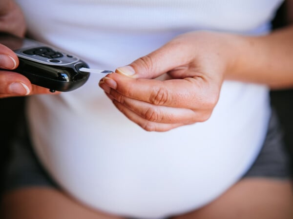 mulher grávida desconhecida com diabetes gestacional colocando sangue no aparelho de glicose para medir o nível de glicose