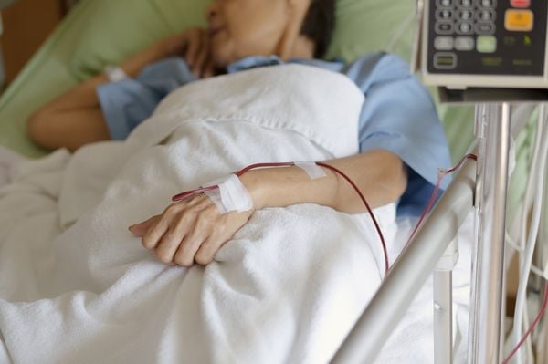 Mulher deitada em leito de hospital fazendo tratamento