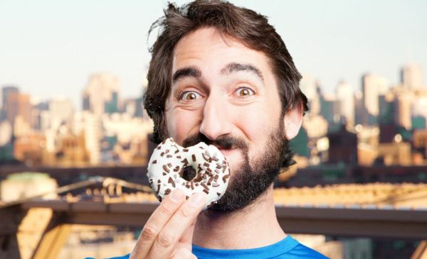 Homem segurando donut mordido