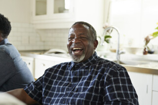 Homem adulto sorrindo enquanto está sentado em casa