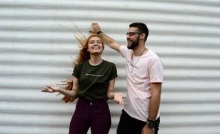 Homem e mulher em frente a um muro branco