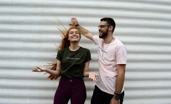 Homem e mulher em frente a um muro branco