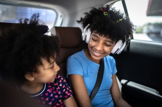 Duas crianças sentadas no banco de trás do carro se olhando