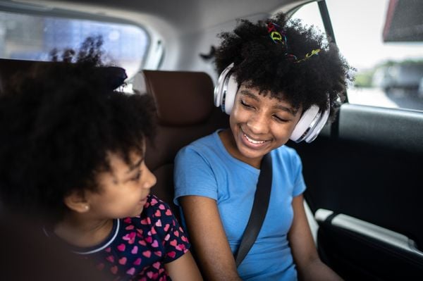 Duas crianças sentadas no banco de trás do carro se olhando