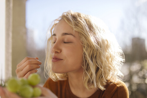 Mulher comendo uva de olho fechado