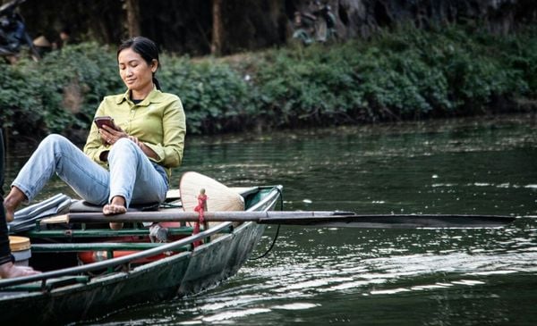 Mulher em um barco mexendo no celular