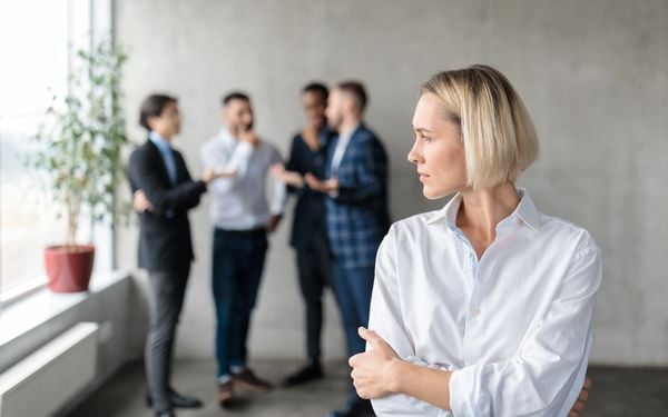 Mulher isolada dos demais colegas de trabalho