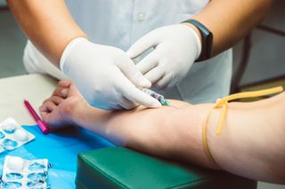 enfermeira colocando agulha no braço de paciente para exame de sangue