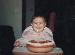 bebê feliz sentada em cadeirinha com um bolo de aniversário na sua frente