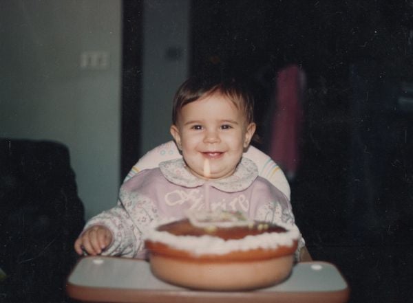 bebê feliz sentada em cadeirinha com um bolo de aniversário na sua frente