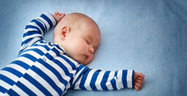 Bebê dormindo com os braços esticados
