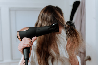 Mulher secando o cabelo com escova e secador