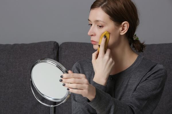 mulher passando casca de banana no rosto