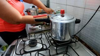 Mulher cozinhanndo feijão em panela de pressão