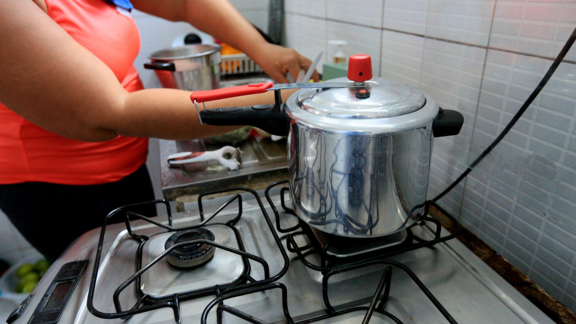 Mulher cozinhanndo feijão em panela de pressão