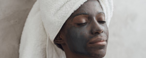 mulher com toalha no cabelo e máscara facial de carvão ativado