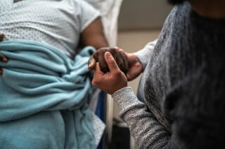Filho segurando a mão do pai no hospital