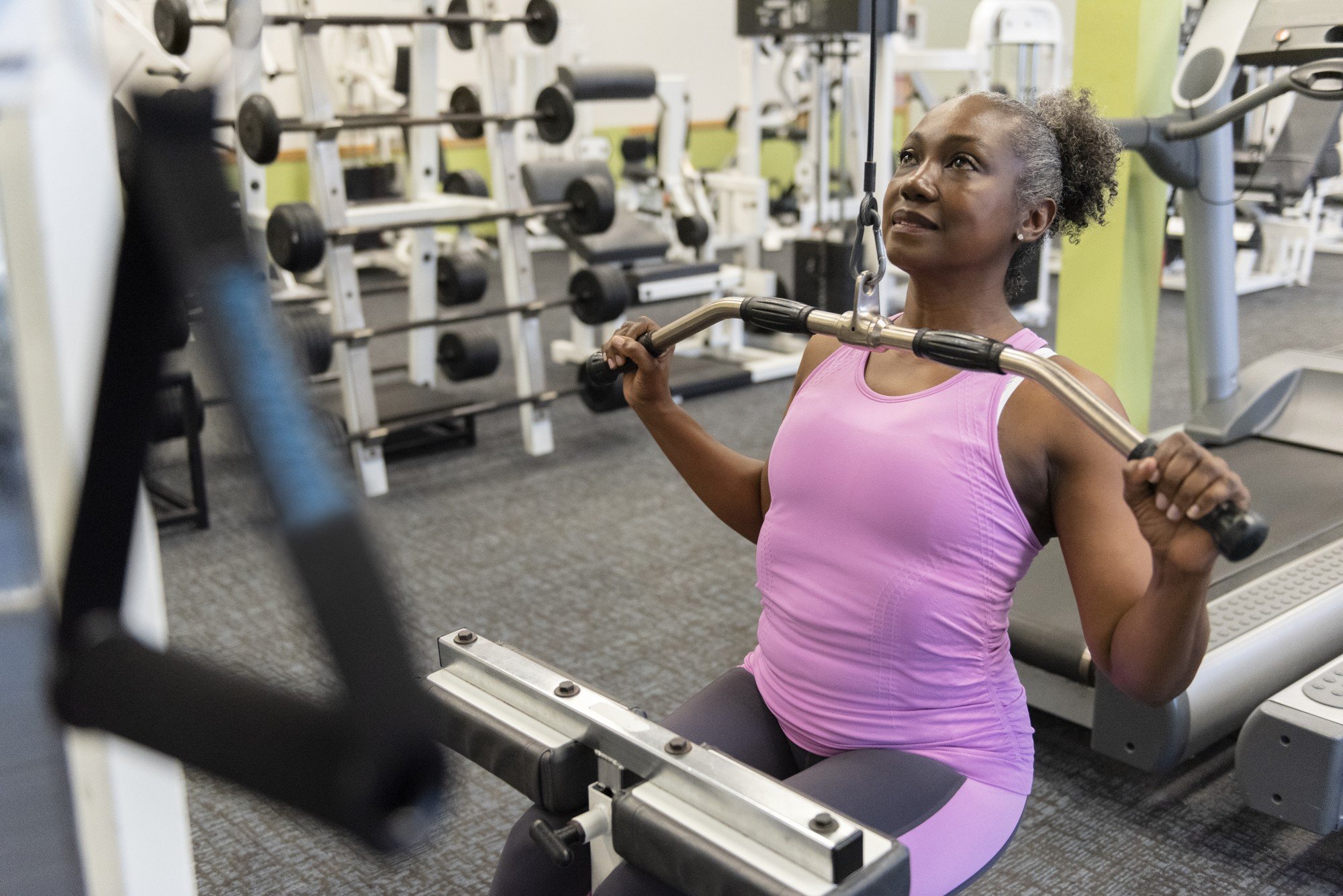 Mulher negra madura fazendo exercício de musculação em um aparelho na academia