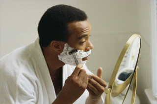 Homem se barbeando na frente do espelho