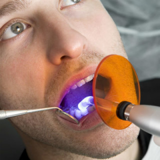 Homem fazendo clareamento dental com luz - Foto: Getty Images