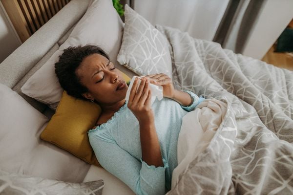 mulher doente deitada na cama com os olhos fechados e segurando um papel nas mãos