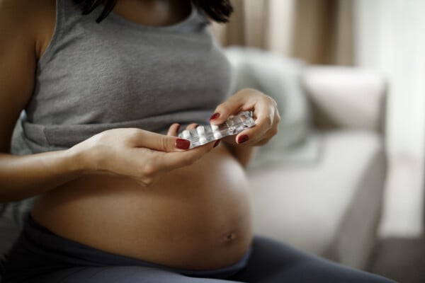 Mulher grávida tomando vitaminas sentada no sofá