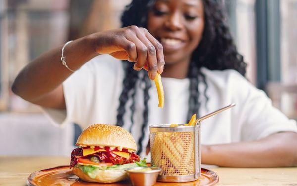 mulher comendo hamburguer com batata frita