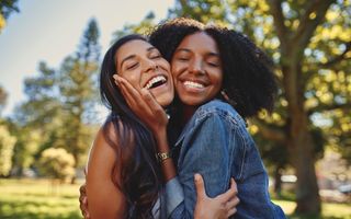 duas amigas dando um abraço e sorrindo