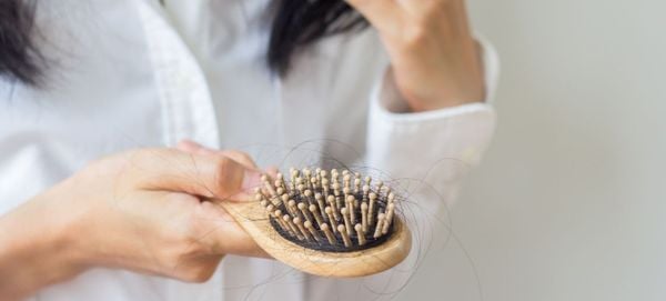 Mulher segura escova de madeira com tufo de cabelos nas cerdas