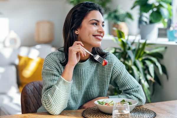 Mulher sorridente comendo salada