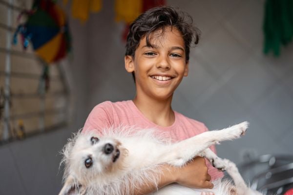 Menino sorridente com seu cachorro no colo