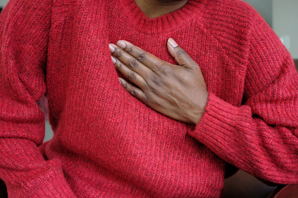 Mulher com suéter vermelho e a mão no peito
