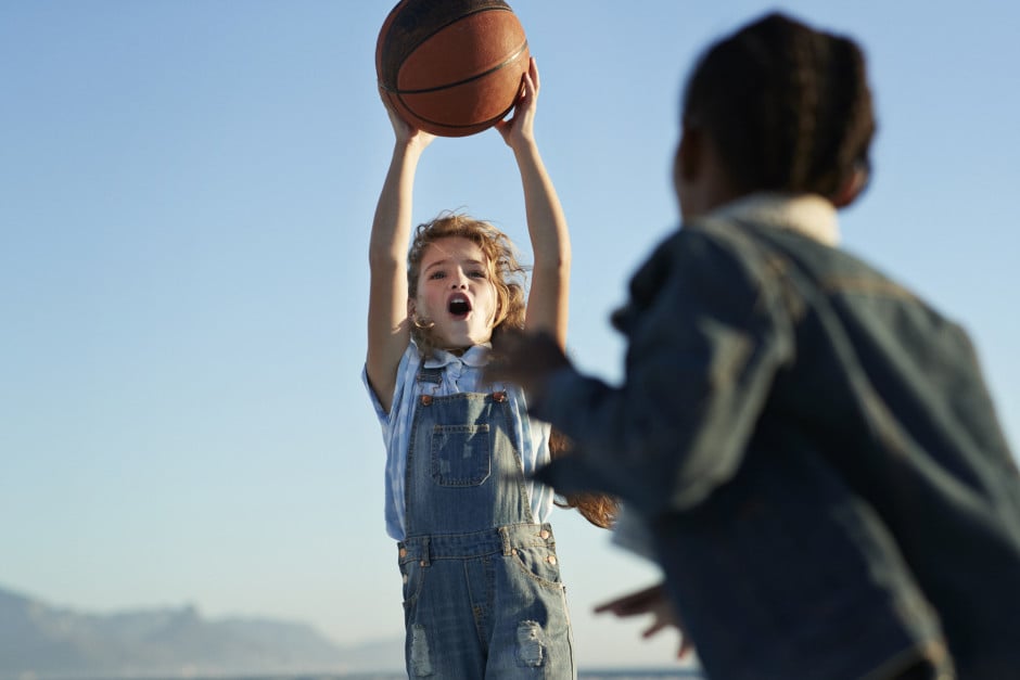 Duas crianças jogando basquete ao ar livre