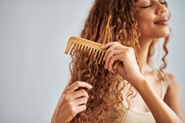 Mulher penteando o cabelo com pente de madeira