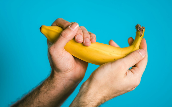 Imagem aproximada de mão masculina segurando uma banana