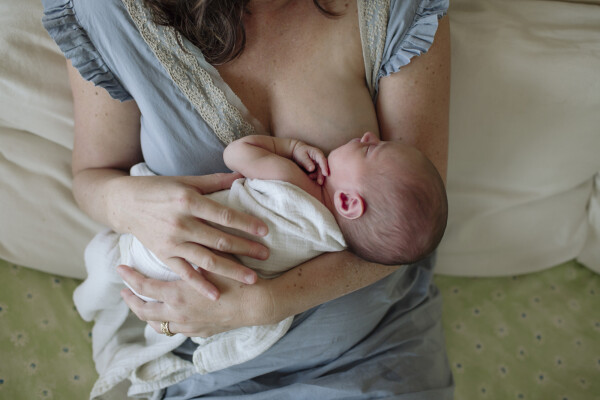 Mulher sentada na cama amamentando bebê