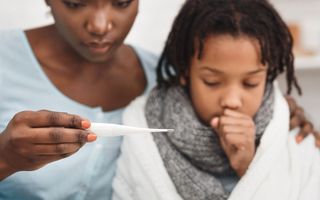 menino doente com tosse e mãe medindo temperatura